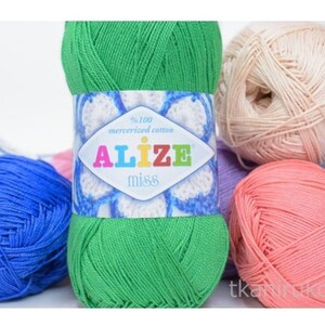 Puede incluir: Una colección de ovillos de hilo Alize Miss de colores. El ovillo principal es verde brillante con una etiqueta que dice "Alize Miss" y "100% algodón mercerizado". Otros ovillos son azules, rosas y beige. Ideal para proyectos de punto y ganchillo.