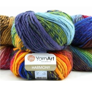 May include: Close-up of several skeins of YarnArt Harmony yarn. The yarn is a mix of colours, including blue, green, purple, orange, and yellow. Each skein has a label that reads "YarnArt HARMONY". The yarn is likely used for knitting or crocheting.