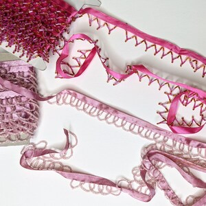 May include: Pink and purple beaded trim with a scalloped edge. The trim is made of small beads and is perfect for adding a touch of elegance to any project.