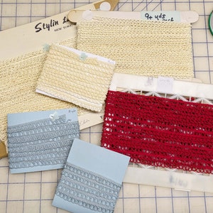 May include: Assortment of lace trim in various colors and lengths.  The trim is made of a delicate crocheted material.  The trim is labeled with the length in yards and the price per yard.  Stylin' Lace, New York.