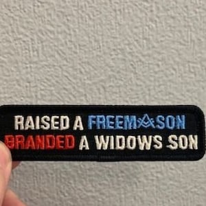 May include: Black patch with white text that reads "RAISED A FREEMASON BRANDED A WIDOWS SON" with red and blue accents.