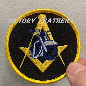 May include: A yellow and black embroidered patch featuring a motorcycle within a square and compass. The text "VICTORY LEATHERS" is visible at the top of the patch.