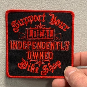 May include: Red and black embroidered patch with the text "Support Your Local Independently Owned Bike Shop".