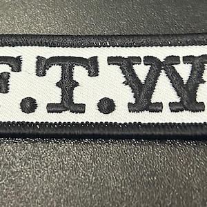 May include: Black and white embroidered patch with the text "F.T.W."