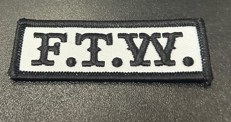 May include: Black and white embroidered patch with the text "F.T.W."