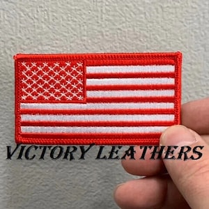 May include: Red embroidered American flag patch with white stars and stripes. The patch has a white stitched border and the text "VICTORY LEATHERS" is visible below the patch.