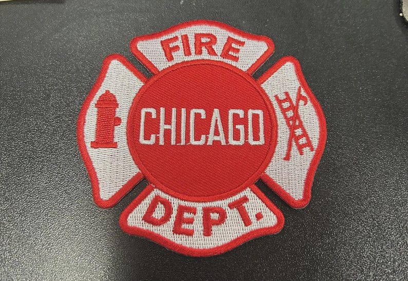 Pu&ograve; includere: Una toppa ricamata circolare con un design a croce di Malta rosso e bianco. Il cerchio centrale mostra il testo CHICAGO in bianco. Le sezioni superiore e inferiore riportano FIRE e DEPT. Un idrante rosso e una scala sono sui pannelli laterali.