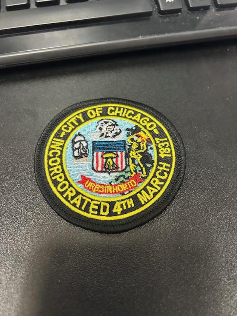 May include: Black and yellow embroidered patch with the text "City of Chicago Incorporated 4th March 1837" and a stylized image of a coat of arms.