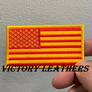 May include: A red and yellow embroidered American flag patch with the text "VICTORY LEATHERS" below it.