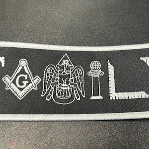 May include: Black and white embroidered patch featuring the word "FAMILY" and Masonic symbols, including a compass and square, an eagle, a column, and a level.