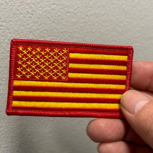 May include: A red and gold embroidered American flag patch.