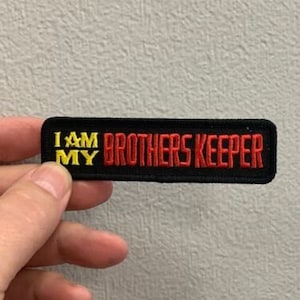 May include: Black embroidered patch with yellow and red lettering that reads "I am my brothers keeper".