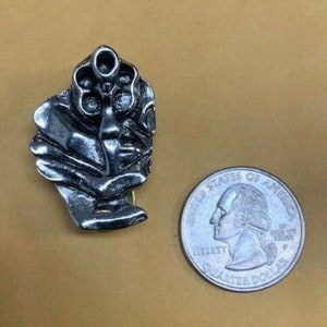 以下が含まれることがあります： 銃を持った手の形をした銀色の金属製のピン。ピンは詳細に作られており、リアルな外観をしています。