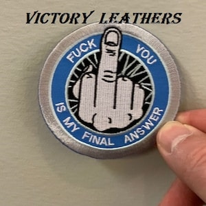 Op de afbeelding: Een geborduurde patch in zilver en blauw met een middelvinger en de tekst "F**k You Is My Final Answer".