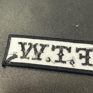 May include: Black and white embroidered patch with the letters "WTF" in white on a black background.