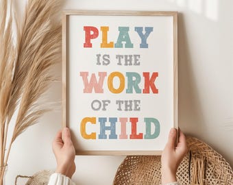 May include: A framed print with the text "PLAY IS THE WORK OF THE CHILD" in colorful, textured letters on a white background.