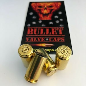 May include: Four gold-colored bullet valve caps. The caps are marked with "Winchester" and "40 S&W".