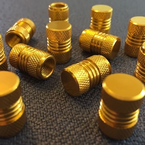 May include: A set of 12 gold metal tire valve stem caps. The caps have a textured design and are a popular accessory for car enthusiasts.