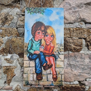 Peut inclure: Une peinture vintage représentant deux enfants assis sur un mur, avec une ville en arrière-plan. Le garçon porte une chemise bleue et un jean, et la fille porte une chemise rouge et une jupe. La peinture est encadrée et présente un ciel bleu avec des nuages blancs.