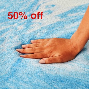 Puede incluir: Una mano presiona un topper de colchón de espuma viscoelástica azul y blanco. El texto "50% de descuento" se muestra sobre la mano.