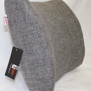 May include: Grey lumbar support cushion with a textured fabric cover. The cushion is shaped to provide support for the lower back. The cushion has a tag with the word "Xeno" on it.