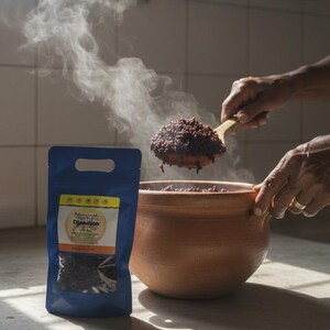 May include: A blue bag of DjonDjon, a type of mushroom, next to a clay pot filled with cooked DjonDjon. Steam rises from the pot and a wooden spoon scoops the food. The image is taken in a kitchen.