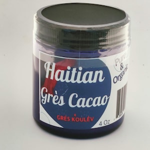 May include: A cylindrical jar of Haitian Grès Cacao, a dark blue paste. The jar has a black lid and a label with white text on a blue background. The label also includes the text "Pure & Organic" and "4 oz".