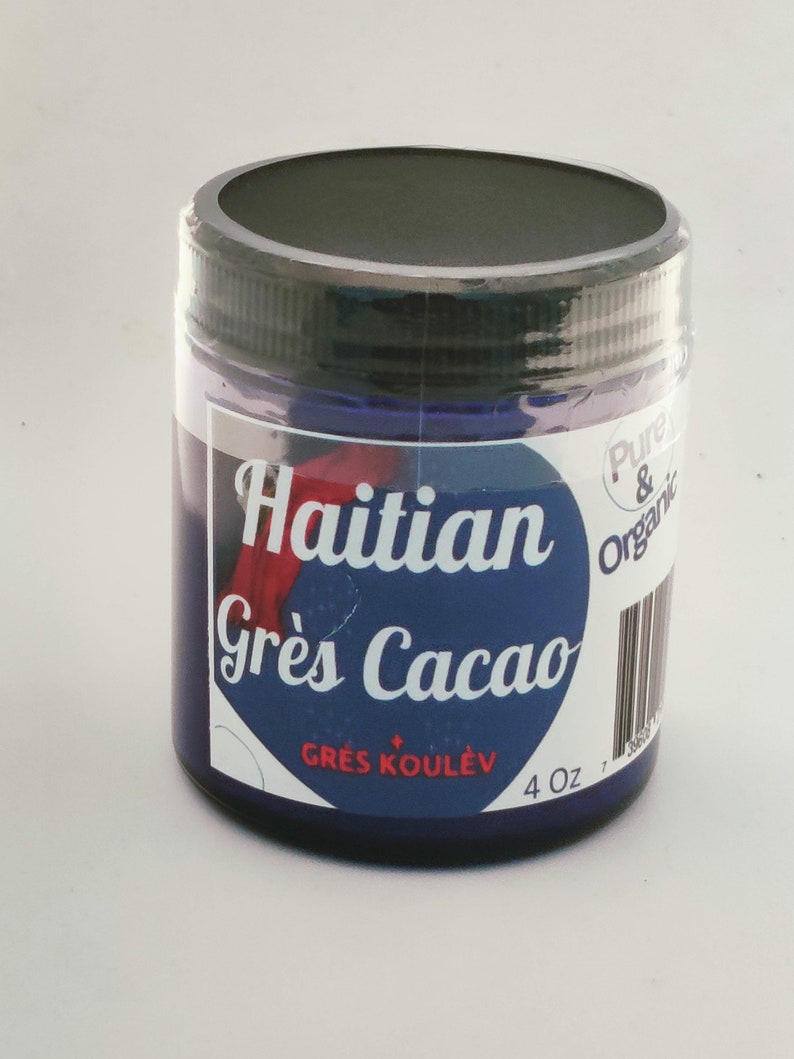Op de afbeelding: Een cilindrische pot Haitian Gr&egrave;s Cacao, een donkerblauwe pasta. De pot heeft een zwart deksel en een etiket met witte tekst op een blauwe achtergrond. Het etiket bevat ook de tekst "Pure & Organic" en "4 oz".
