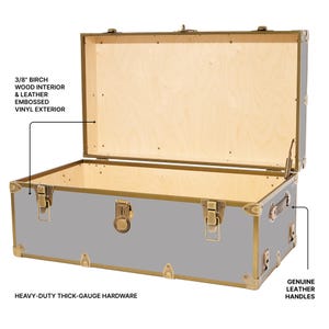 May include: A gray trunk with a light wood interior and brass-colored hardware. The trunk has genuine leather handles and embossed vinyl exterior. The text on the image says "3/8" birch wood interior & leather embossed vinyl exterior" and "heavy-duty thick-gauge hardware."