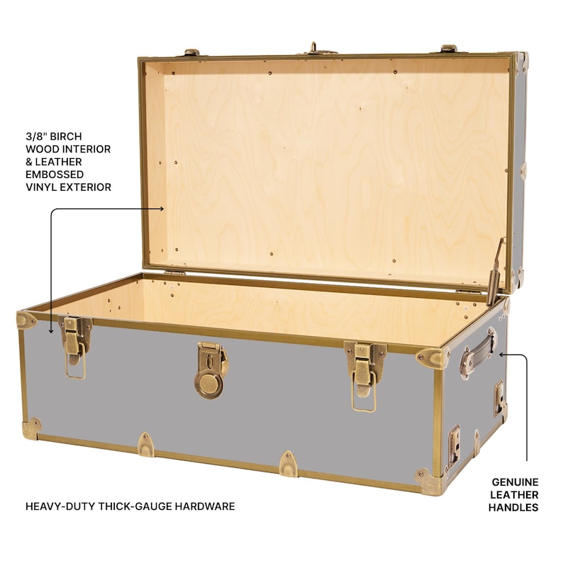 May include: A gray trunk with a light wood interior and brass-colored hardware. The trunk has genuine leather handles and embossed vinyl exterior. The text on the image says "3/8" birch wood interior & leather embossed vinyl exterior" and "heavy-duty thick-gauge hardware."