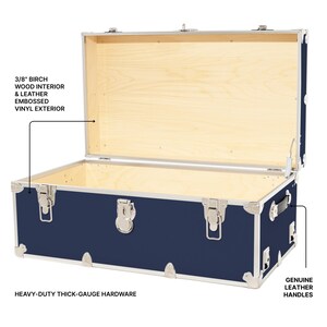 May include: A navy blue trunk with a light wood interior and silver hardware. The trunk features genuine leather handles and embossed vinyl exterior. The text reads: 3/8" birch wood interior & leather embossed vinyl exterior, heavy-duty thick-gauge hardware, and genuine leather handles.