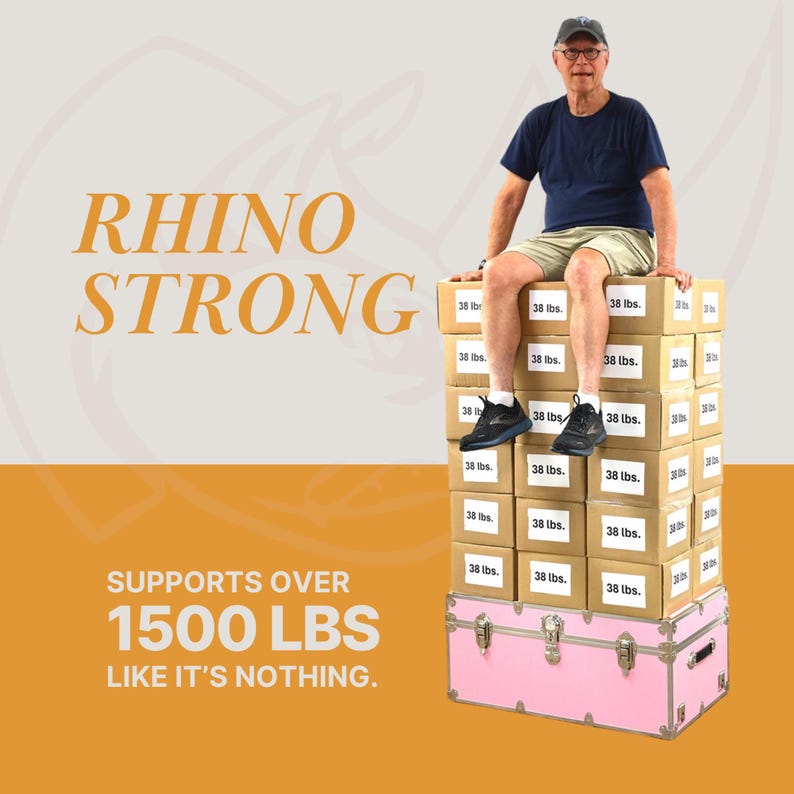 Puede incluir: Una persona mayor est&aacute; sentada encima de una pila de cajas de cart&oacute;n y un ba&uacute;l rosa. Las cajas est&aacute;n etiquetadas como "38 lbs." La imagen incluye el texto "RHINO STRONG" y "SUPPORTS OVER 1500 LBS LIKE IT'S NOTHING."