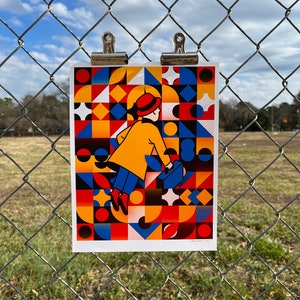 Puede incluir: Una impresión geométrica colorida con una persona con un abrigo amarillo y un sombrero rojo caminando con una maleta. La impresión es una mezcla de formas geométricas rojas, amarillas, azules, negras y blancas.