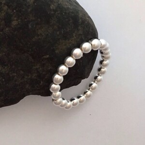 May include: A silver ring made of small, round beads.