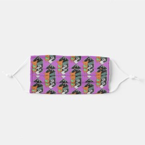 May include: A purple face mask with a repeating pattern of a brown dog wearing a teal bandana and a black and white mountain scene. The dog is standing on a white background.