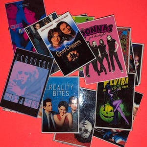 May include: A collection of miniature movie posters, including "Gold Diggers", "Reality Bites", and "Elvira: Mistress of the Dark". The posters are arranged on a bright red background, showcasing various film titles and imagery.