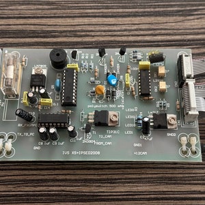 May include: A green circuit board with various electronic components, including resistors, capacitors, integrated circuits, and LEDs. The board has text that reads "IUS XS+IPSE02008" and "polyswitch 500 mA".