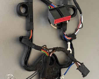 May include: A black plastic automotive wiring harness with multiple colored wires, connectors, and a black plastic frame. The harness includes red, white, blue, green, and brown wires, and various connectors.