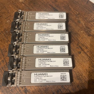 May include: Six silver-colored network transceivers with black plastic ends. Each transceiver has a label with the text "HUAWEI" and information about the device, including the model number, serial number, and "Made in China".