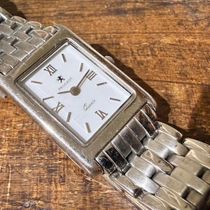 May include: A white ceramic mug with a black handle and the text "But First, Coffee" in a black, bold font. The mug is on a white surface.