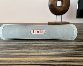 May include: A silver Beats by Dr. Dre portable Bluetooth speaker with a red "beats" logo.
