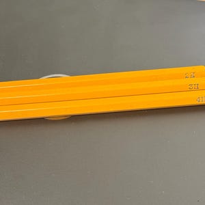 Op de afbeelding: Drie gele potloden met zwarte markeringen aan de zijkant. De markeringen luiden "4H", "5H" en "6H".