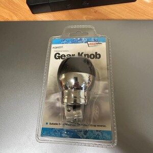 Può includere: Un pomello del cambio nero e argento con il testo "Gear Knob" e "PO#4331" sulla confezione. La confezione include anche il testo "streetwize Professional Solutions".