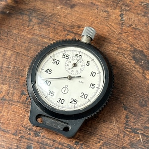 May include: A black stopwatch with a white face and black hands. The face has numbers from 5 to 60, and the hands are pointing to 35 seconds and 0 minutes.