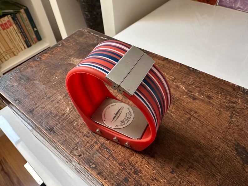 Op de afbeelding: Een rood-zwart gestreept polshorloge met een zilveren metalen band en een witte wijzerplaat. De wijzerplaat van het horloge heeft een onderzee&euml;r-ontwerp en de tekst "Limited Edition" erop.