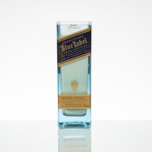 Pu&ograve; includere: Una bottiglia di vetro trasparente con un'etichetta blu che recita "JOHNNIE WALKER Blue Label BLENDED SCOTCH WHISKY" e "BOTTLE NO. FD7 19945".