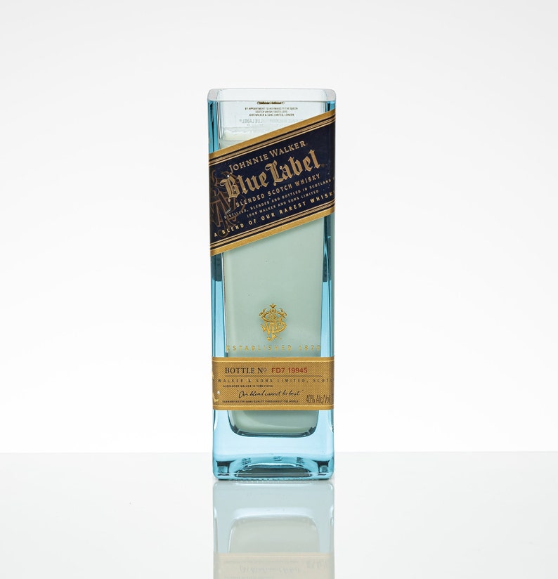 Pu&ograve; includere: Una bottiglia di vetro trasparente con un'etichetta blu che recita "JOHNNIE WALKER Blue Label BLENDED SCOTCH WHISKY" e "BOTTLE NO. FD7 19945".