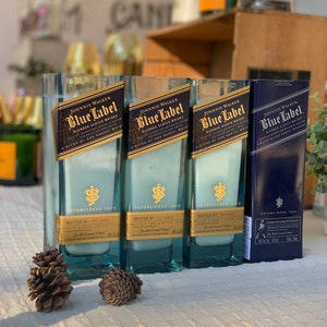 Pu&ograve; includere: Tre bottiglie di vetro blu con un'etichetta blu che recita "Johnnie Walker Blue Label Blended Scotch Whisky Established 1820". Le bottiglie sono riempite con un liquido bianco e hanno un tappo dorato.