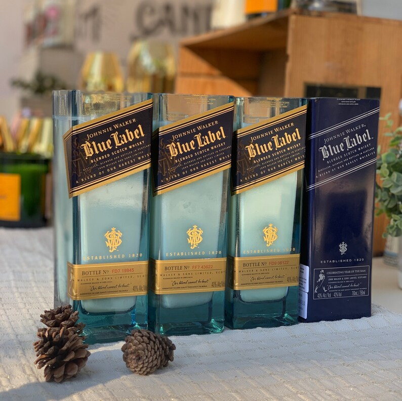 Pu&ograve; includere: Tre bottiglie di vetro blu con un'etichetta blu che recita "Johnnie Walker Blue Label Blended Scotch Whisky Established 1820". Le bottiglie sono riempite con un liquido bianco e hanno un tappo dorato.