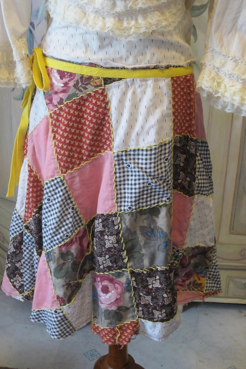 Op de afbeelding: Een patchwork rok met een gele strik. De rok is gemaakt van verschillende stoffen in roze, rood, bruin en wit.